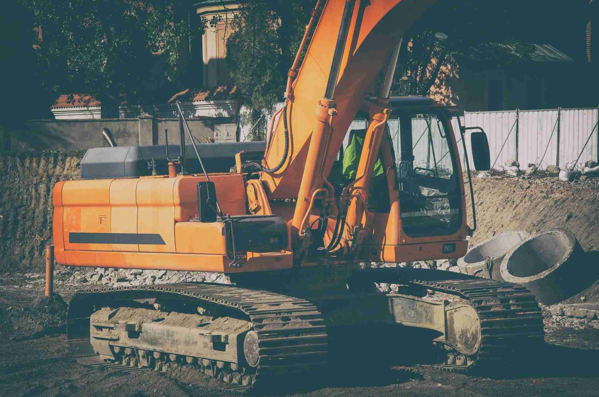 An excavator working on a construction site next to pipe