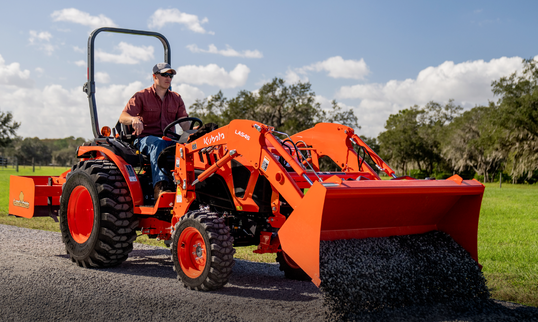 Kubota LX compact tractor with a front loader carrying gravel