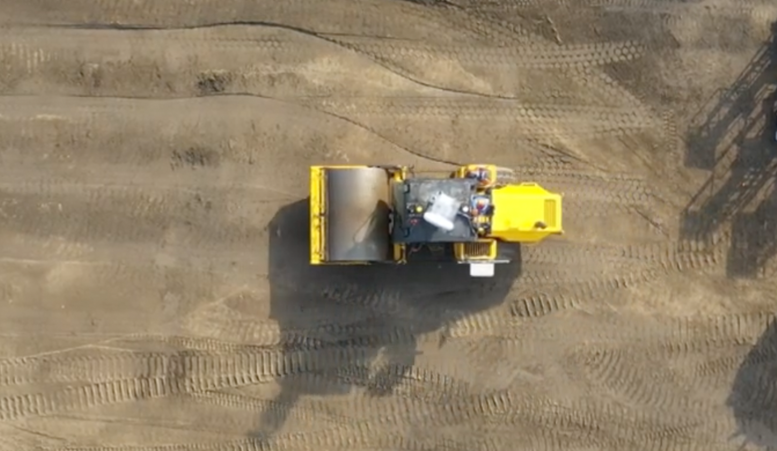 Overhead view of a roller compacting a graded pad