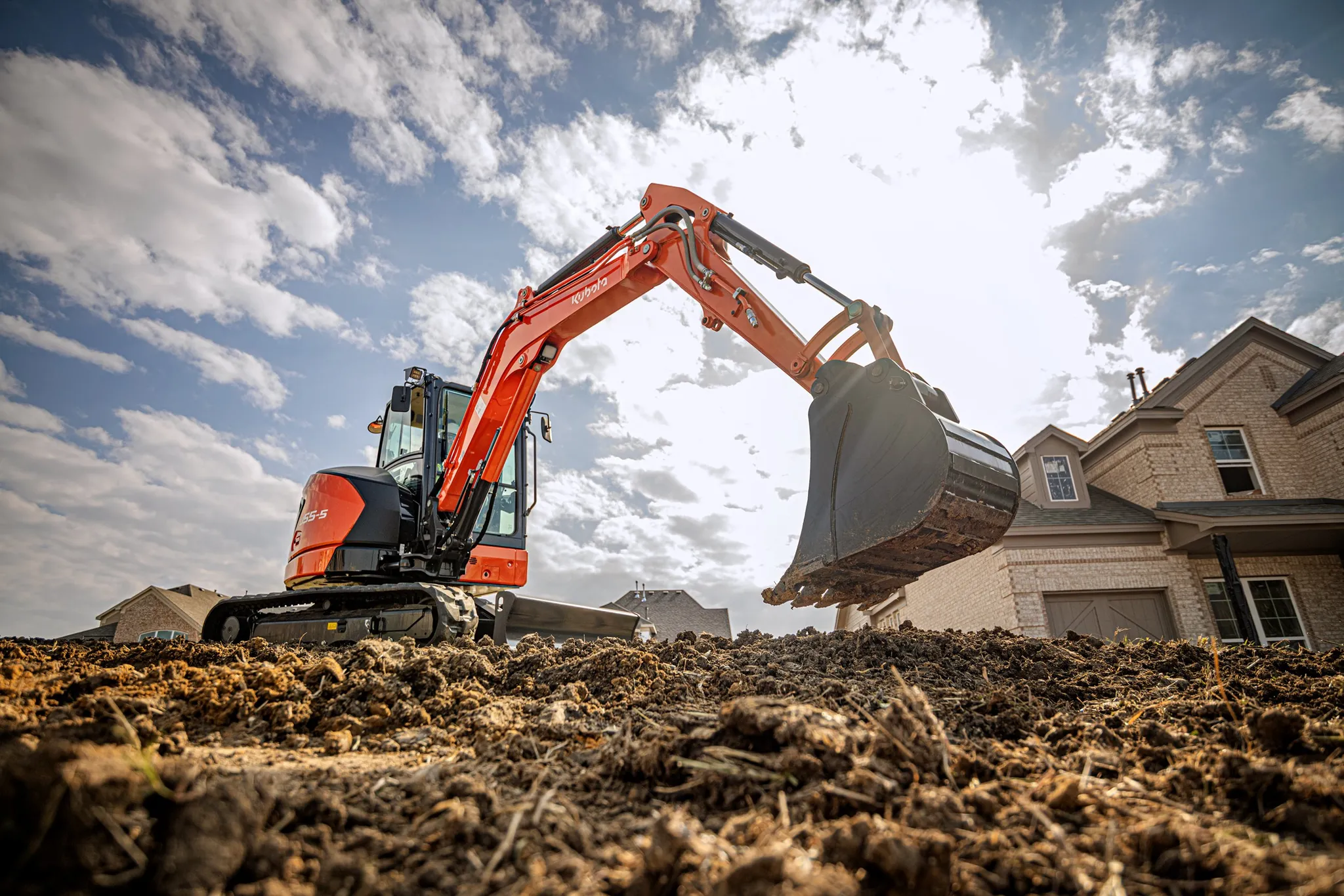 Kubota U55 mini excavator digging in front of a two-story house