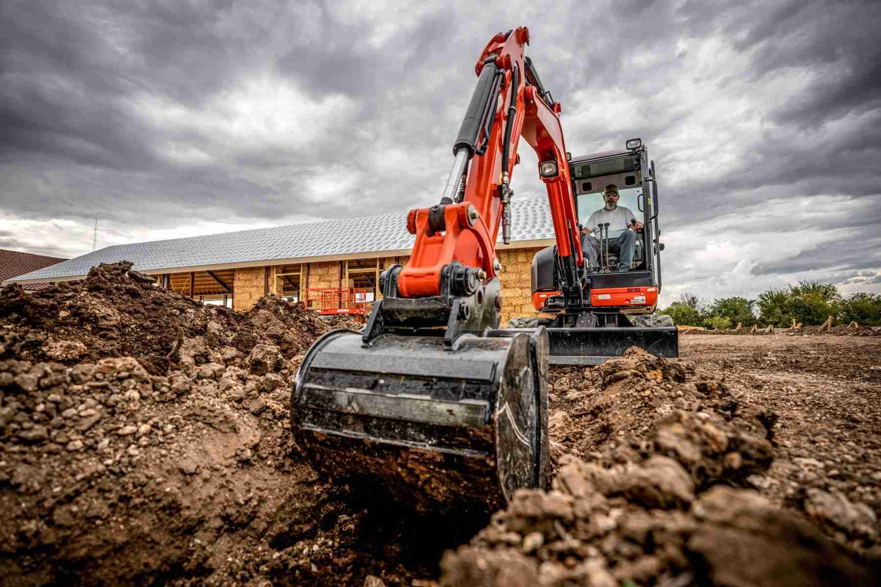 Kubota mini excavator digging with a bucket in dirt