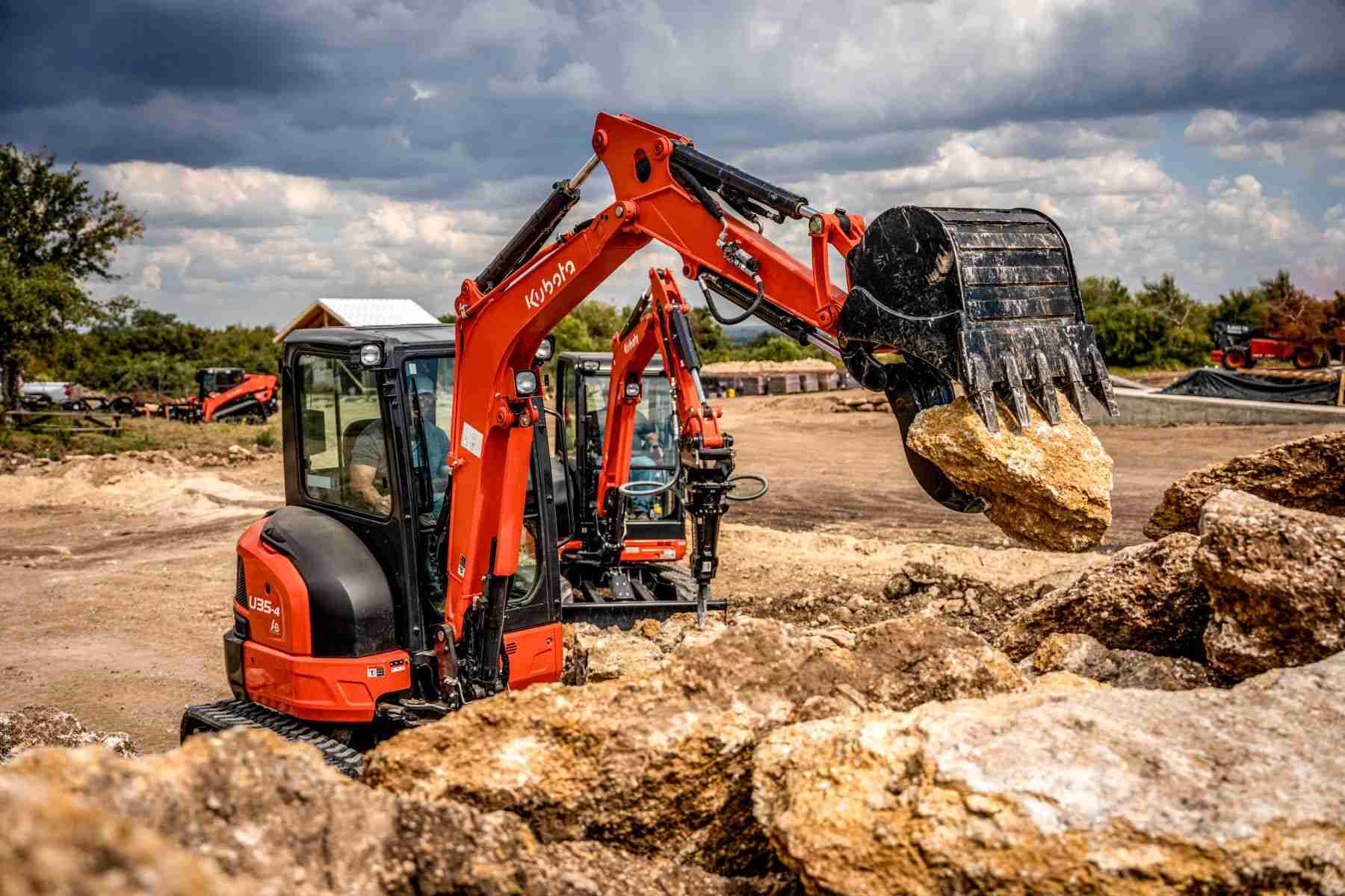 Kubota mini excavator with a hydraulic thumb holding a rock