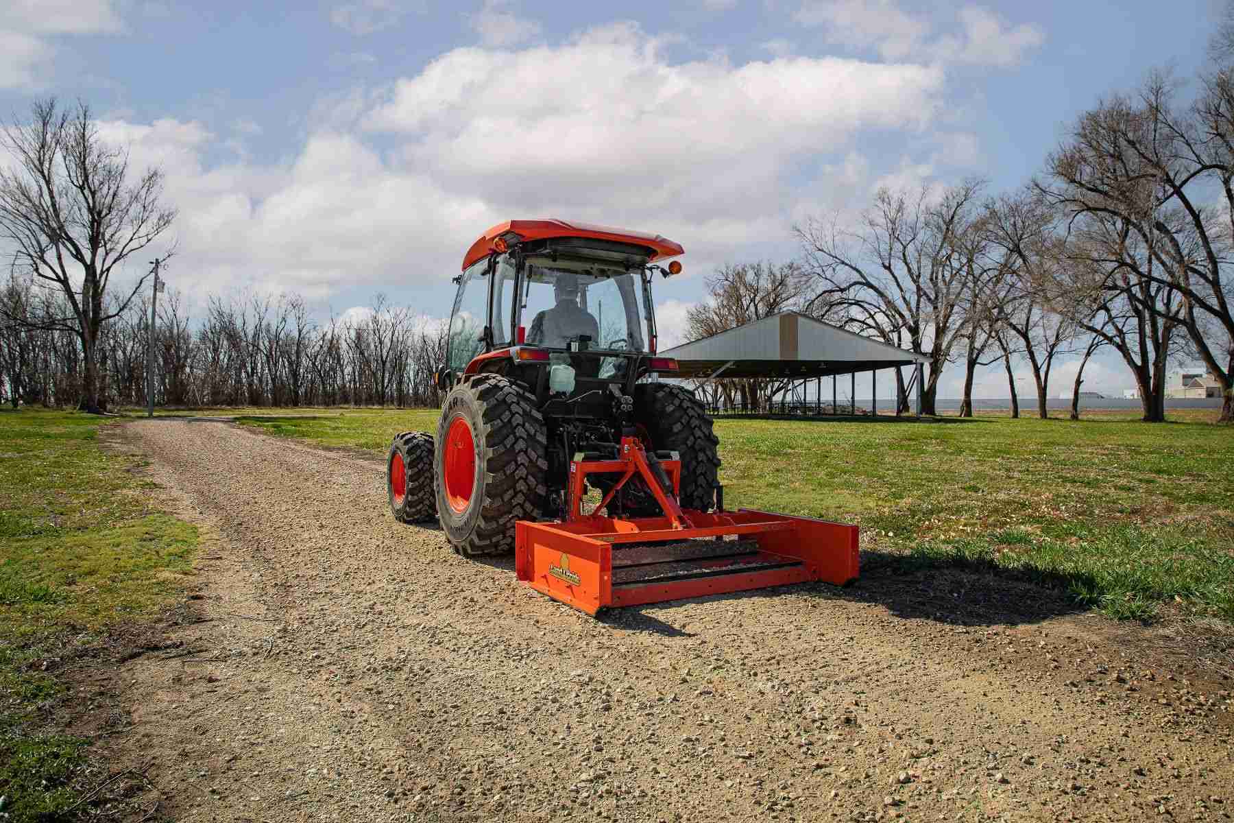 Kubota tractor pulling a land plane on a gravel drive